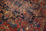 Textured detail of vintage Karaja carpet's geometric floral cross-sections in gem-tone red and navy.