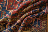 Draped hand-knotted Karaja carpet with navy, ruby red, and gold gem tones, showing painted floral motifs.