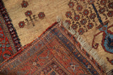 Antique Afshar rug corner revealing hand-knotted back weave, tattered fringe, and ivory ground pattern.