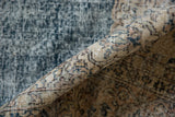 Distressed vintage Sparta carpet's rolled edge, highlighting worn pile, knot heads, and faded blue, beige hues.