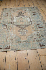 Distressed Oushak rug: central finned floral and ram's horn motif in beige, blue, brown.