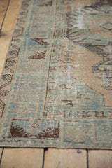 Distressed texture of a vintage Oushak rug, showing faded denim blue and mint green patterns.