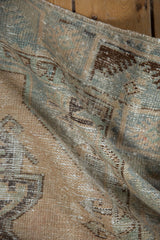 Textured distressed pile of vintage Oushak rug in muted beige, blue, and brown.