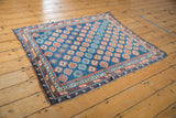 Antique Caucasian rug corner showing sapphire blue geometric gul patterns and original side cord selvage.