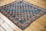 Antique Caucasian rug corner: sapphire blue field, ruby red diminutive guls, geometric borders, fringe.