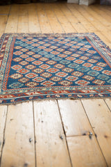 Fringe and geometric border detail on an antique Caucasian rug, featuring rich sapphire, ruby, ivory.