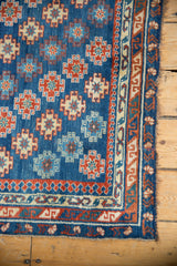 Antique Caucasian rug corner with geometric gul motifs, ruby red border, and intact selvage.