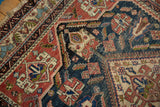 Geometric and floral motifs on antique Afshar carpet in navy, terracotta, ivory, revealing foundation.