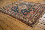 Antique Afshar rug corner with geometric terracotta borders and dusty teal field patterns.