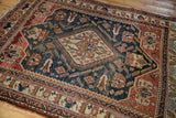 Antique Afshar carpet corner showing terracotta geometric border and dark dusty teal field wear.