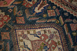Antique Afshar carpet showing ivory geometric contour, terracotta floral motifs on a dark blue field.