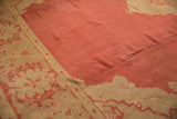 Dust brick red field and antique ivory border on vintage Oushak, featuring serrated leaf palmette motif.