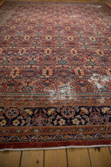 Vintage Mahal carpet detail: dusty cherry red field, henna plant motifs, navy border, foundation visible.
