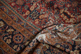 Folded vintage Persian Mahal carpet with henna plant motif, brick red, navy, ivory.