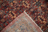 Mahal rug folded corner, showing detailed henna plant motif, dusty red pile, and woven foundation.