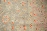 Worn pile detail of distressed Sivas rug, featuring silver floral field and blush pink border.