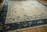 Antique Peking carpet corner with indigo blue border, ivory floral vinery, and a butterfly spandrel.