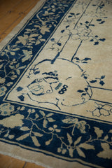 Corner detail of antique Chinese Peking rug with ivory field, indigo blue vinery, roses, butterfly.