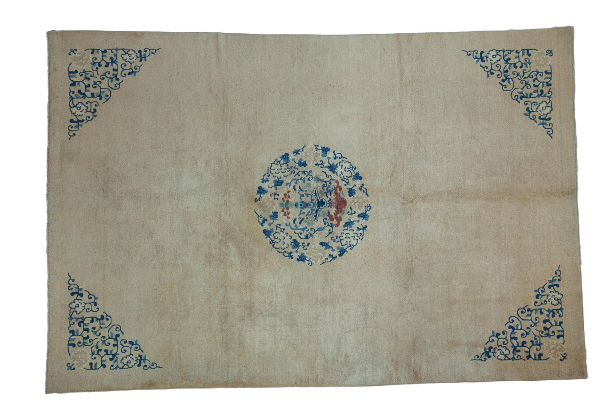 Antique Peking carpet with a central blue roundel medallion and scrolling spandrels on an ivory open field.