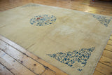 Angled view of the antique Peking carpet's beige field, central roundel, and detailed blue corner spandrels.