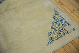 Corner spandrel detail of an antique Peking carpet with blue scrolling vinery on an even ivory pile.