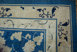 Corner of an antique Peking carpet: cobalt blue field, ivory cloudband border, scrolling floral vinery.