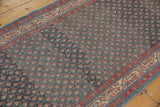 Distressed texture and repeating botehs on a vintage Persian runner with visible color abrashes.