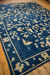 Antique Peking carpet detail: ivory butterflies, blossoms, and a geometric indigo blue border.