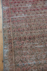 Vintage Malayer runner detail: distressed pale red botehs, charcoal accents, visible foundation, and selvage.