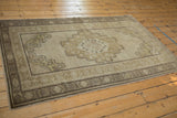 Vintage distressed Oushak rug corner, showing geometric borders and muted beige, earthy brown tones.