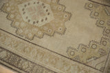 Distressed Oushak rug corner with faded beige field and stepped geometric border.