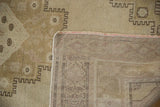 Distressed vintage Oushak rug corner revealing low beige pile, subtle geometric motifs, and its woven foundation.