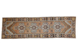 Distressed vintage Oushak runner with repeating medallions on an abrashed orange ground, 3'1