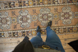 Distressed Oushak runner showing repeating medallions, abrashed ground, gold, and ivory tones.