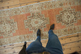 Vintage distressed Oushak runner, terracotta hues, sandalwood and beige geometric medallions, visible worn pile.