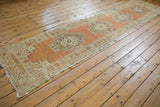 Angled view of distressed Oushak runner showing terra cotta stepped medallions and worn texture.