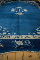 Peking carpet border detail: indigo blue, ivory, and silver floral motifs, with fringe.