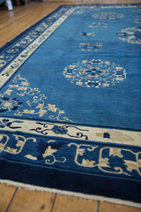 Vintage Peking carpet corner showcasing indigo blue meandering vines, ivory floral motifs, and fringe.