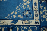 Close-up of vintage Peking carpet corner: blue field, ivory pictorial border, lotus flowers, and vines.