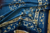 Crumpled section of a Peking rug, revealing pictorial border with blue book and vines.