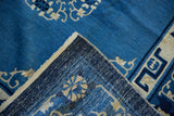 Peking carpet corner revealing blue floral pile, ivory motifs, and hand-knotted foundation.