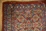 Tattered corner of an antique Bijar runner with woven script detail in the dark red outer border.
