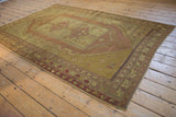 Distressed Oushak carpet texture with foundation showing through its gold and floral patterns.