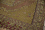 Vintage Oushak rug corner revealing muted gold field and zigzag geometric border patterns.