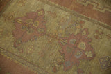 Worn pile texture of a distressed Oushak rug featuring gold, saffron, and mauve finned floral patterns.