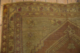 Vintage distressed Oushak carpet's pile showing mostly even wear in gold and aubergine.