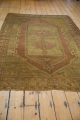 Frayed fringe and low pile texture of a vintage Distressed Oushak rug in gold and mauve.