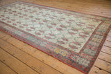 Angled view of a vintage Oushak runner showing its distressed floral lattice pattern and slate-colored border.