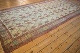 Angled perspective of a distressed vintage Oushak runner's repeating floral lattice pattern.