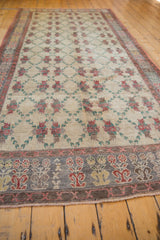 Angled view of a distressed Oushak runner's slate and red border next to the ivory lattice field.